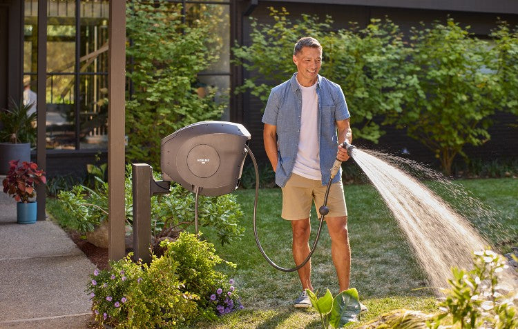 man watering garden with retractable hose reel