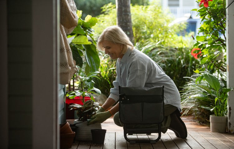 woman kneeling on garden kneeler planting flowers