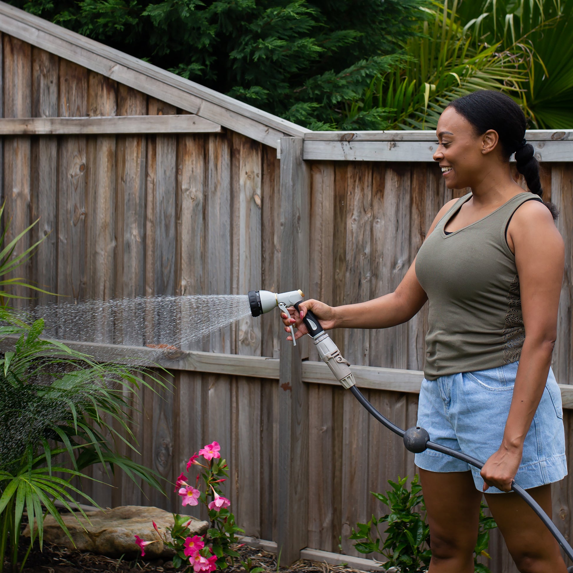 female watering garden plants using the 7 function spray gun