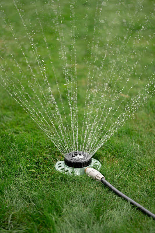 Green 9-Pattern Sprinkler turned on watering the lawn