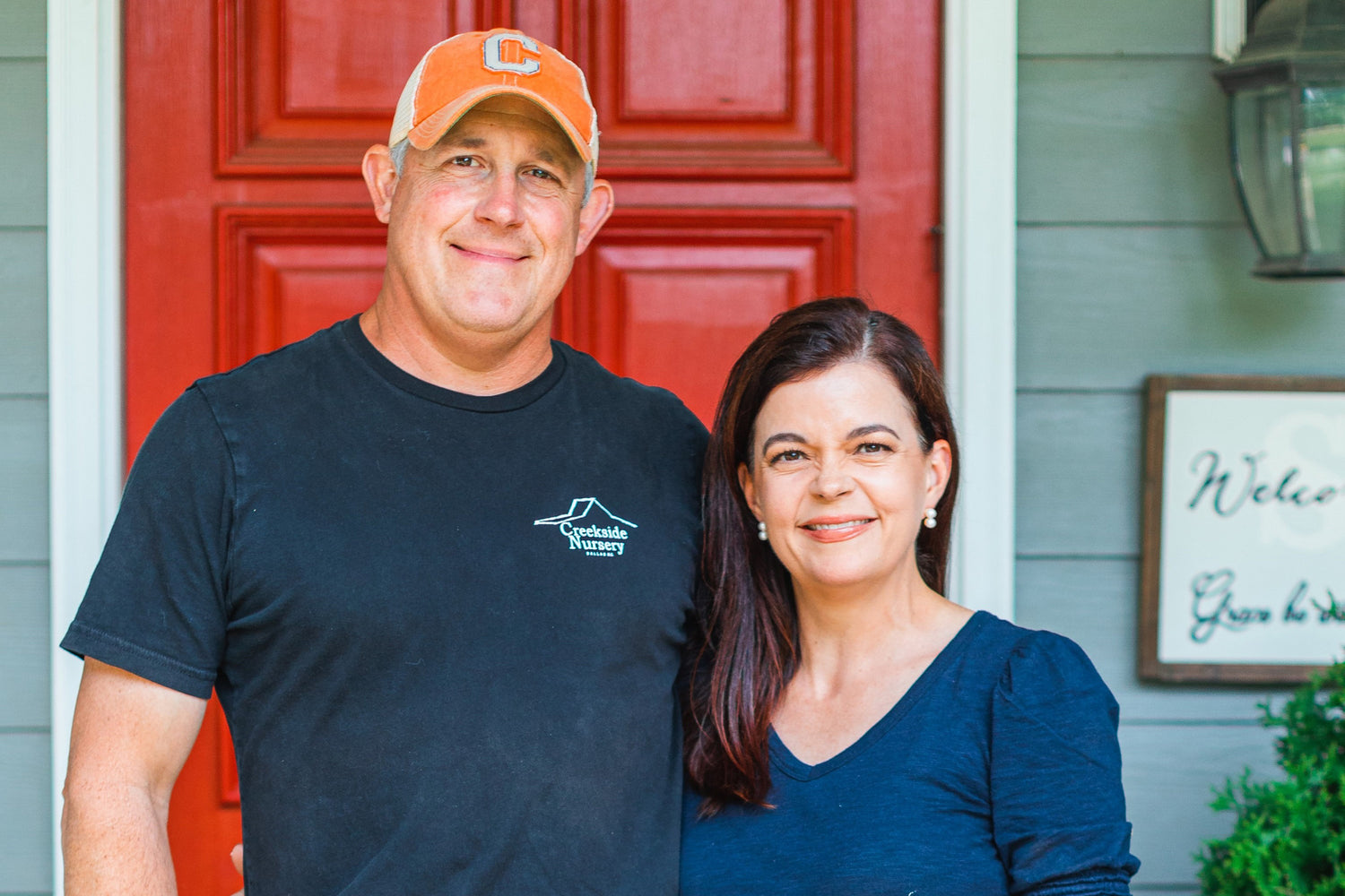 Owners of Creekside Nursery Jerry and Jenny Simpson standing together in front of red door
