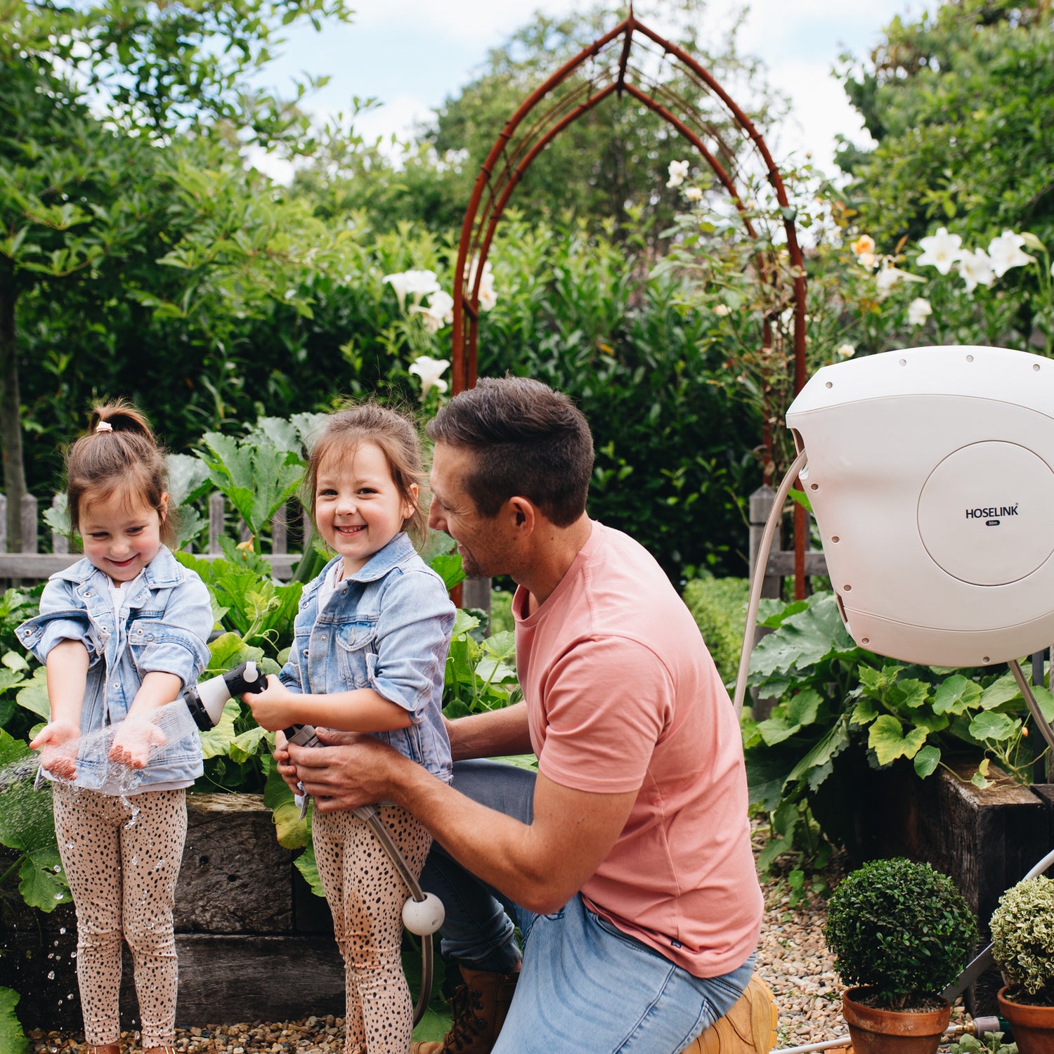 a father watering the garden with his twin girls using Hoselink's Retractable Hose Reel