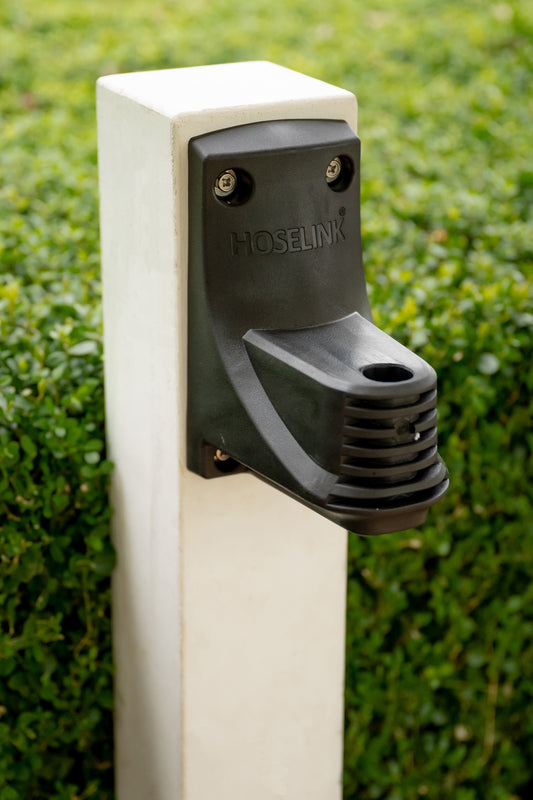 hose reel bracket mounted to a post in a garden