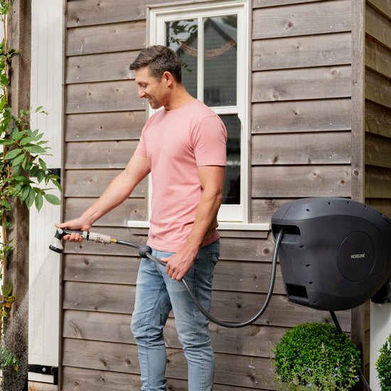 man-watering-garden-with-charcoal-hose-reel