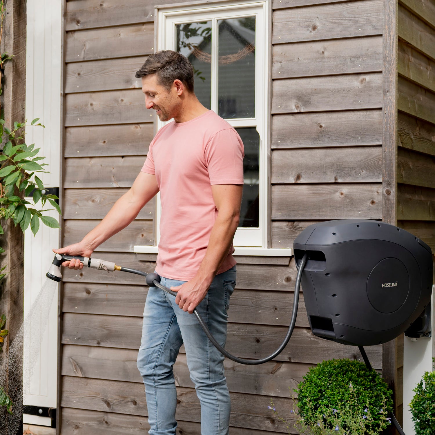 Man watering his garden with a retractable hose reel