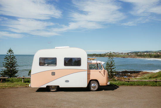 pink-and-white-rv-parked-in-front-of-beach