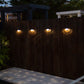four round solar lights installed on a wooden wall with the lights showing a sun beam pattern beneath them