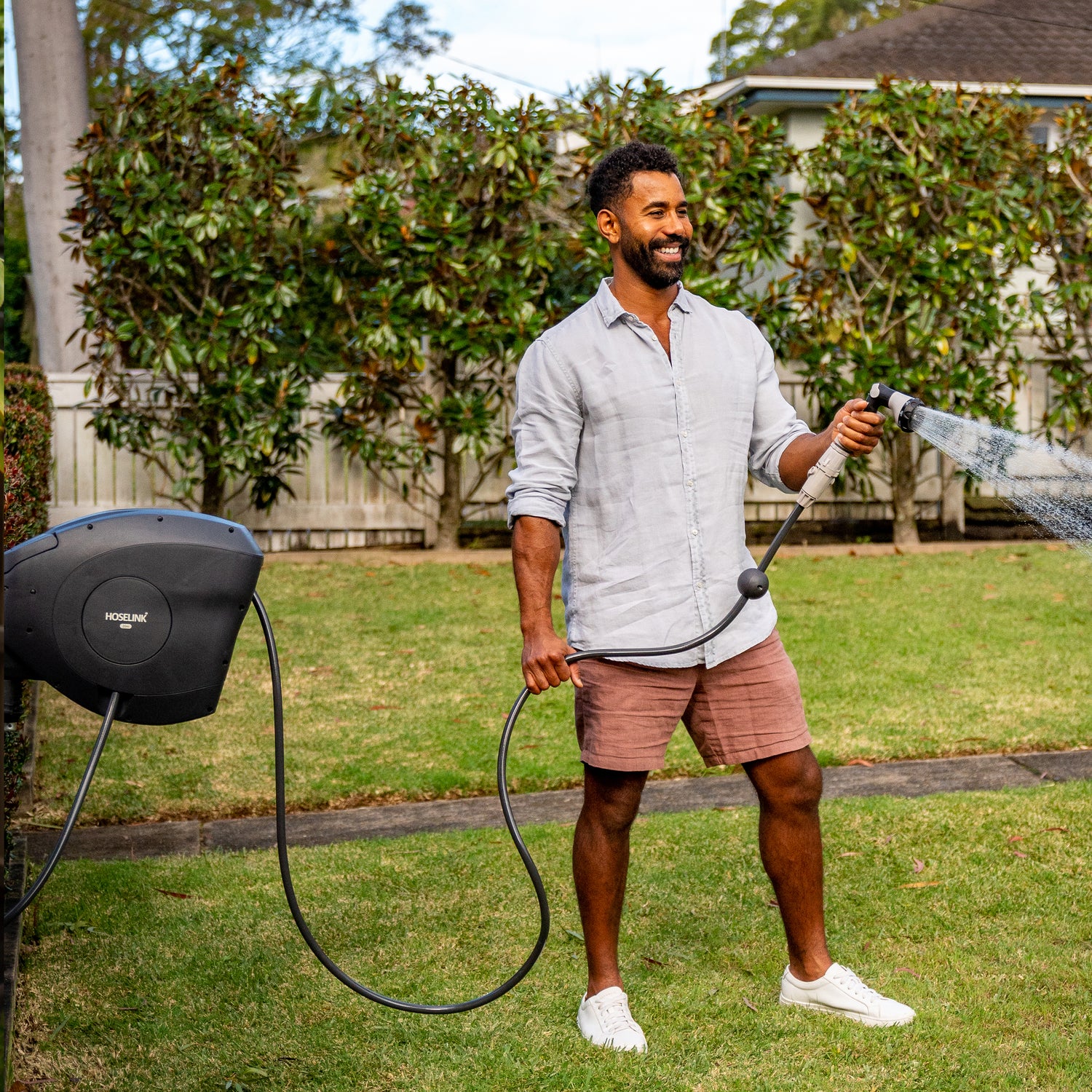 Man watering the garden lawn with a retractable hose reel