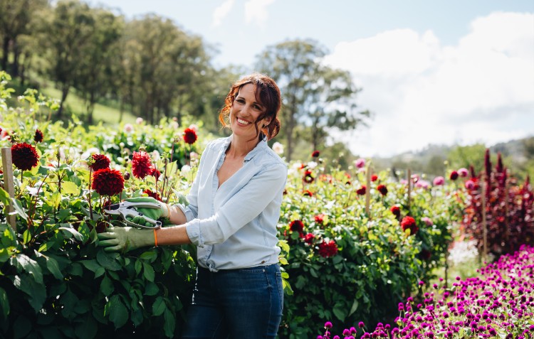 woman cutting flowers in a field and smiling