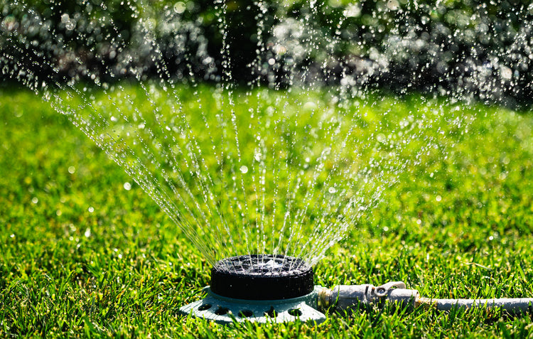 Metal 9-Pattern Spinkler spraying water on green lawn