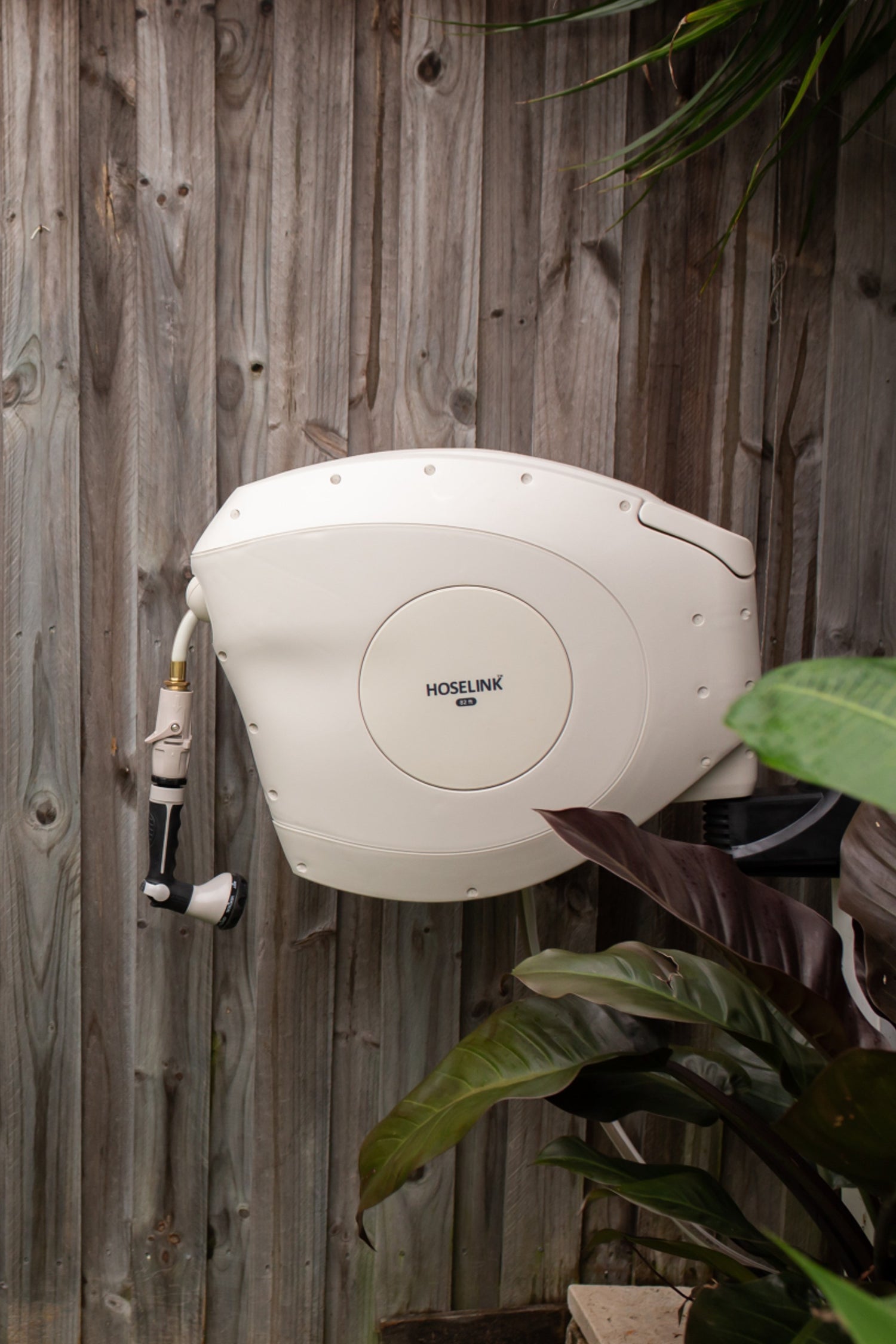 beige-retractable-hose-reel-mounted-to-a-fence