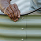 Close-up of hand installing rubber trim along the top edge of a green garden bed