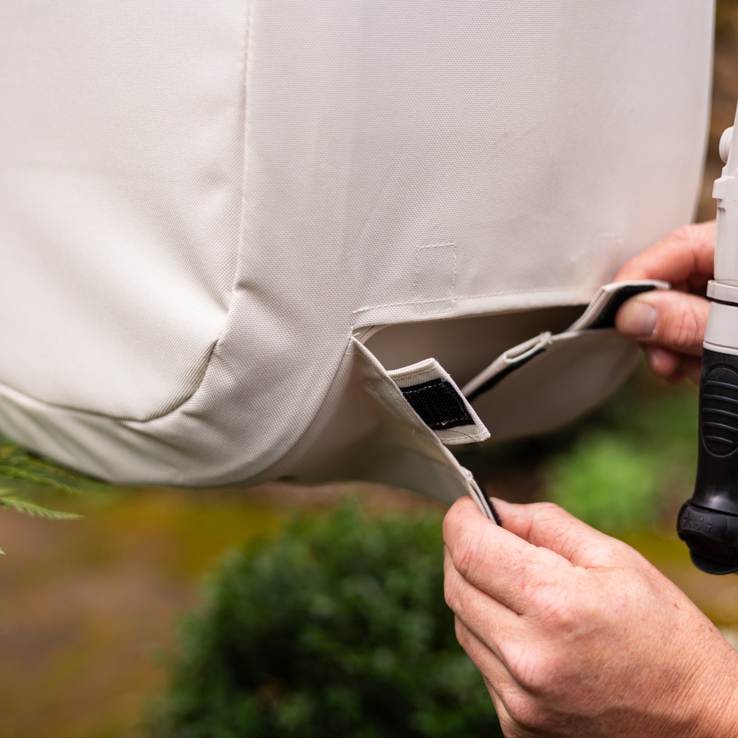 Person attaching velcro tabs at front of beaige Evolve Hose Reel Cover