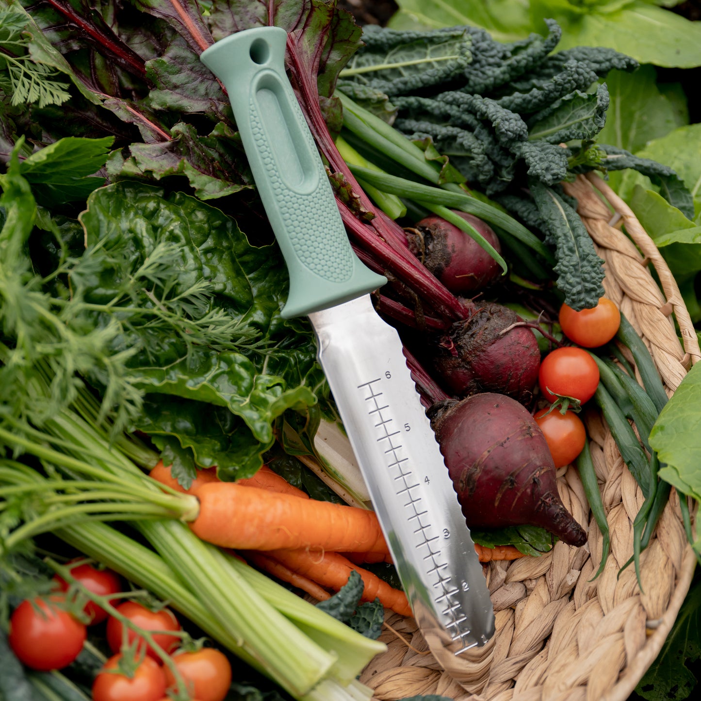garden knife lying in a basket on top of fresh produce