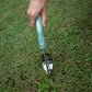 Hand using a Garden Weeder tool to pull weeds from grass