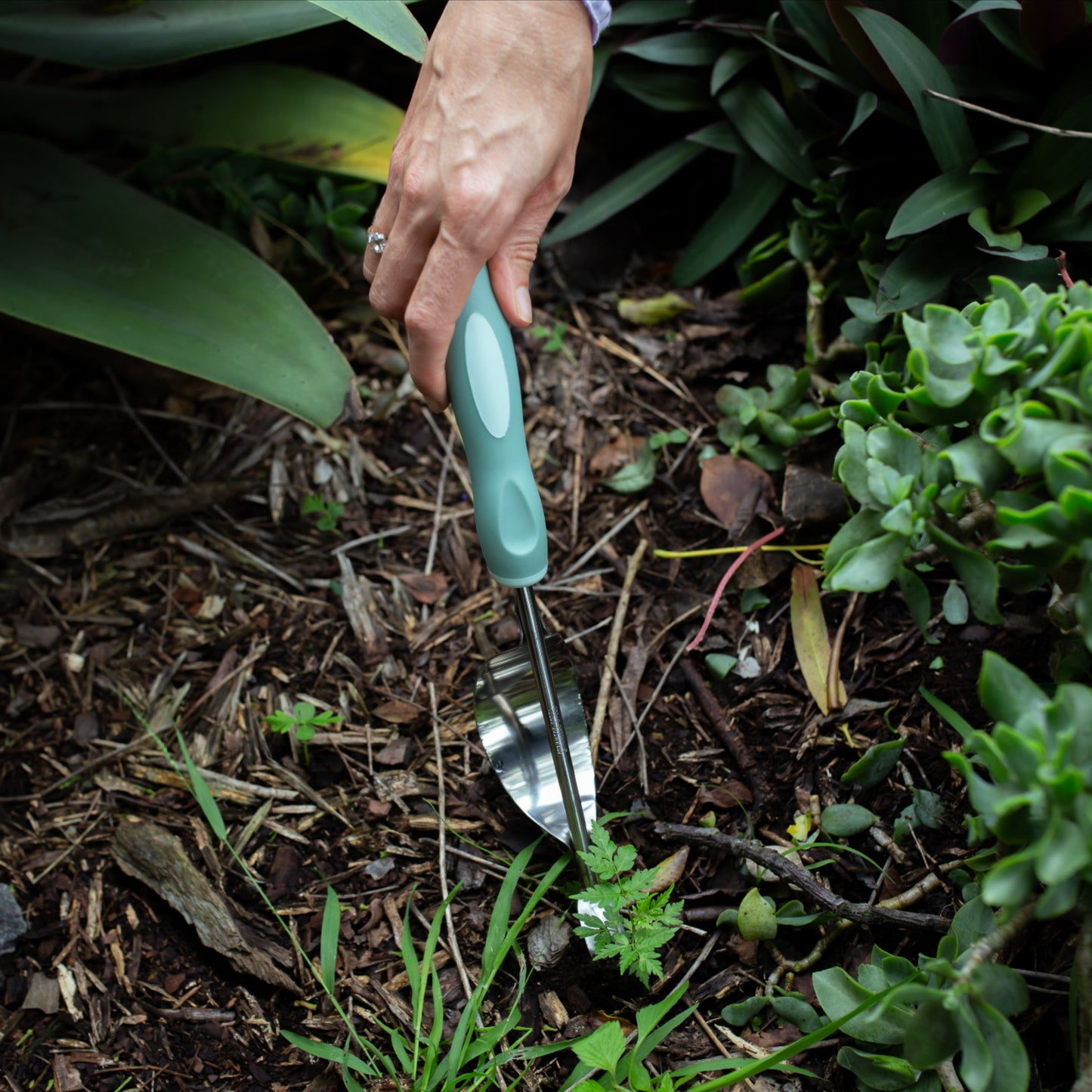 Person using a Garden Weeder tool in a garden setting