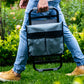 Person walking with folded up garden kneeler and seat across lawn with garden in background