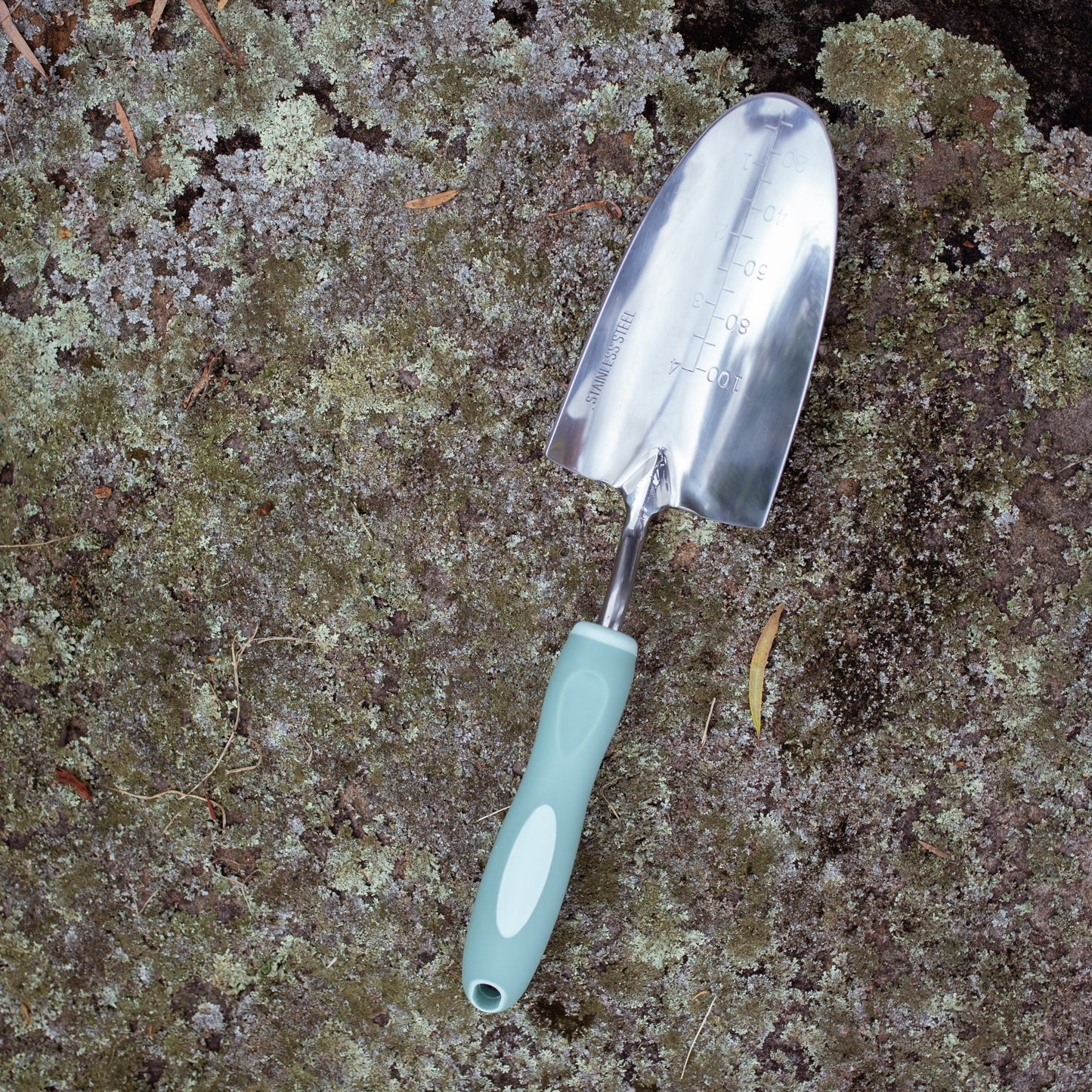 Gardening trowel with a sage green handle on a textured ground surface
