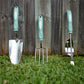 Garden tool set with green handles on grass against a wooden fence.