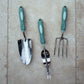 Garden tool set with green handles on a beige surface