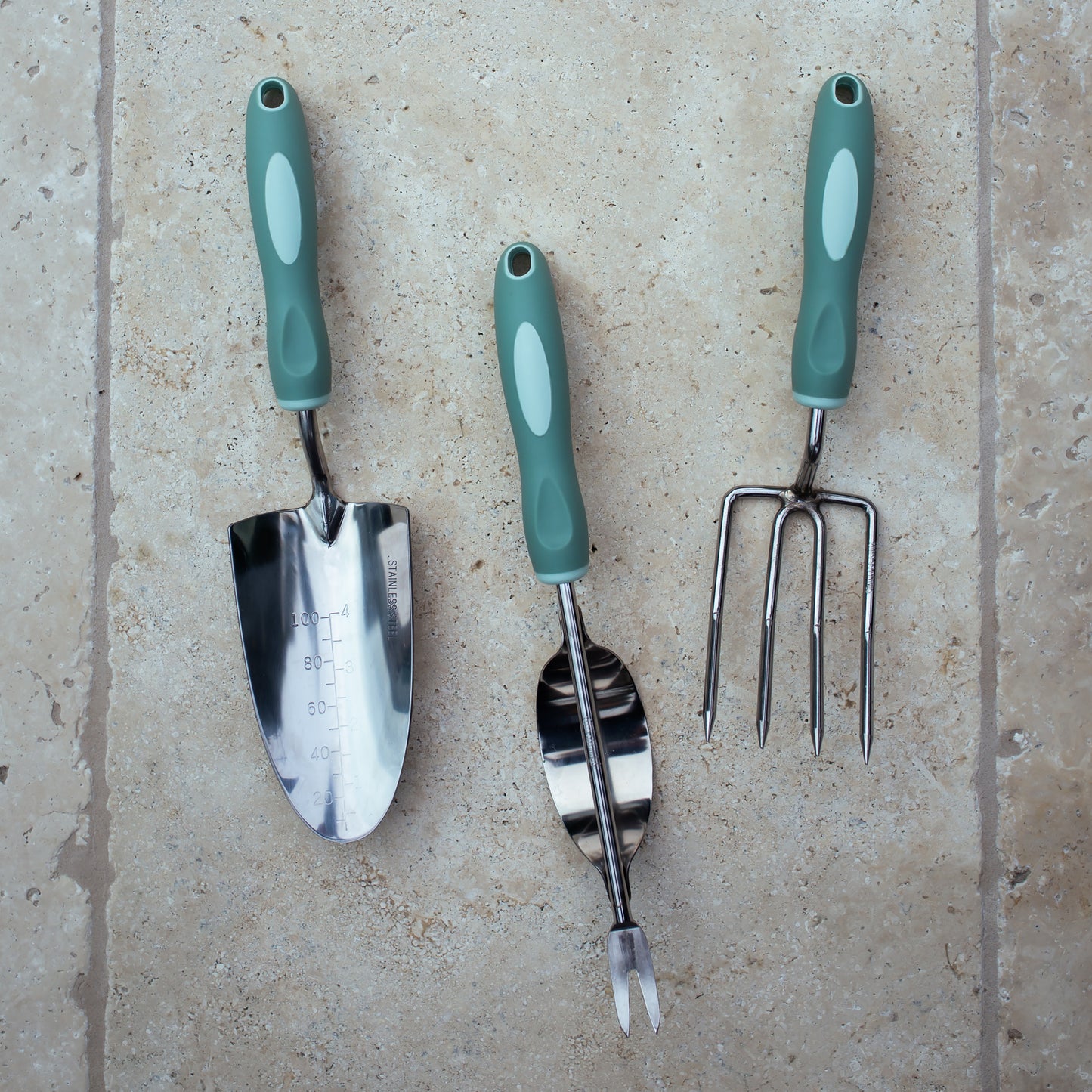 Garden tool set with green handles on a beige surface