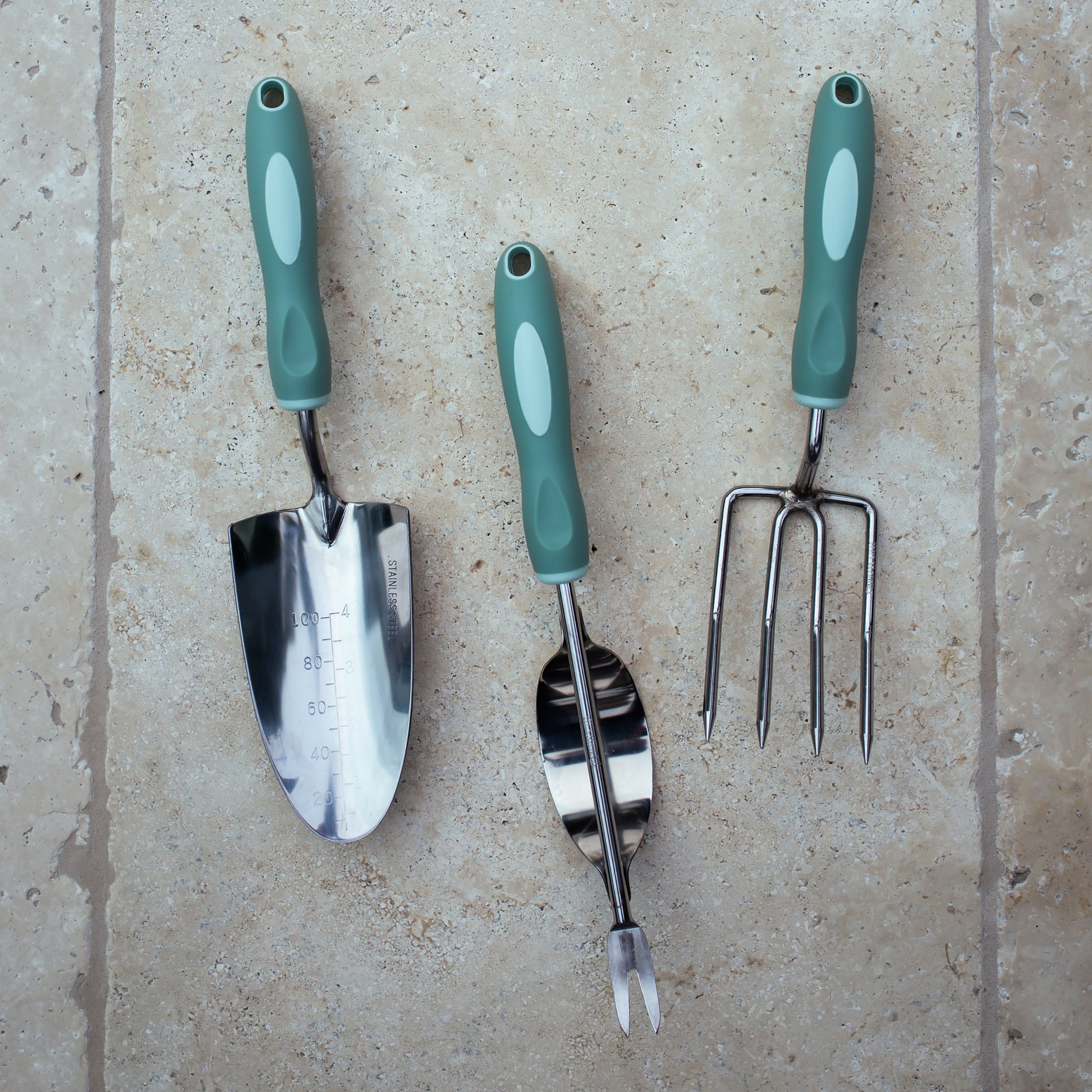 Garden tool set with green handles on a beige surface