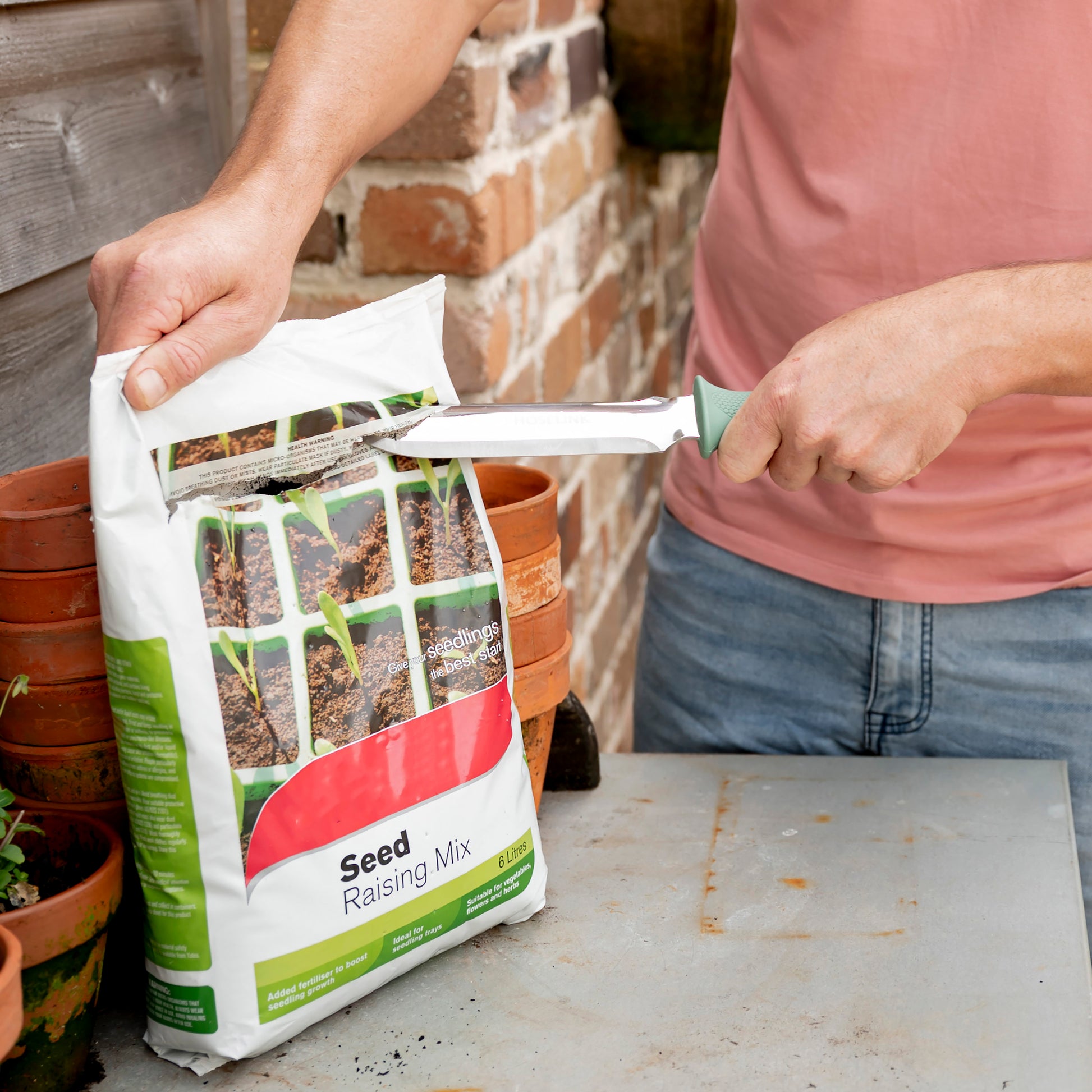 Man using Garden Knife to slice open bag of seed raising mix