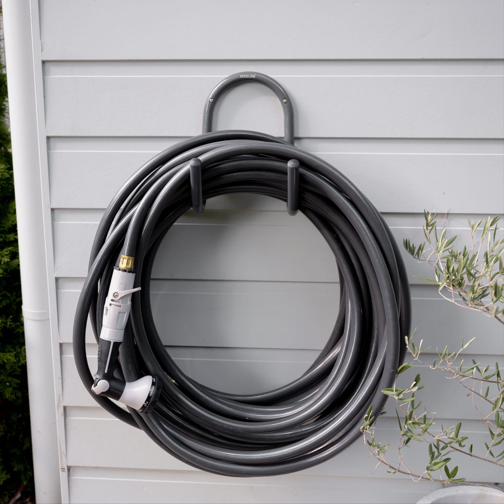 Charcoal hose and hanger mounted on white weatherboard wall