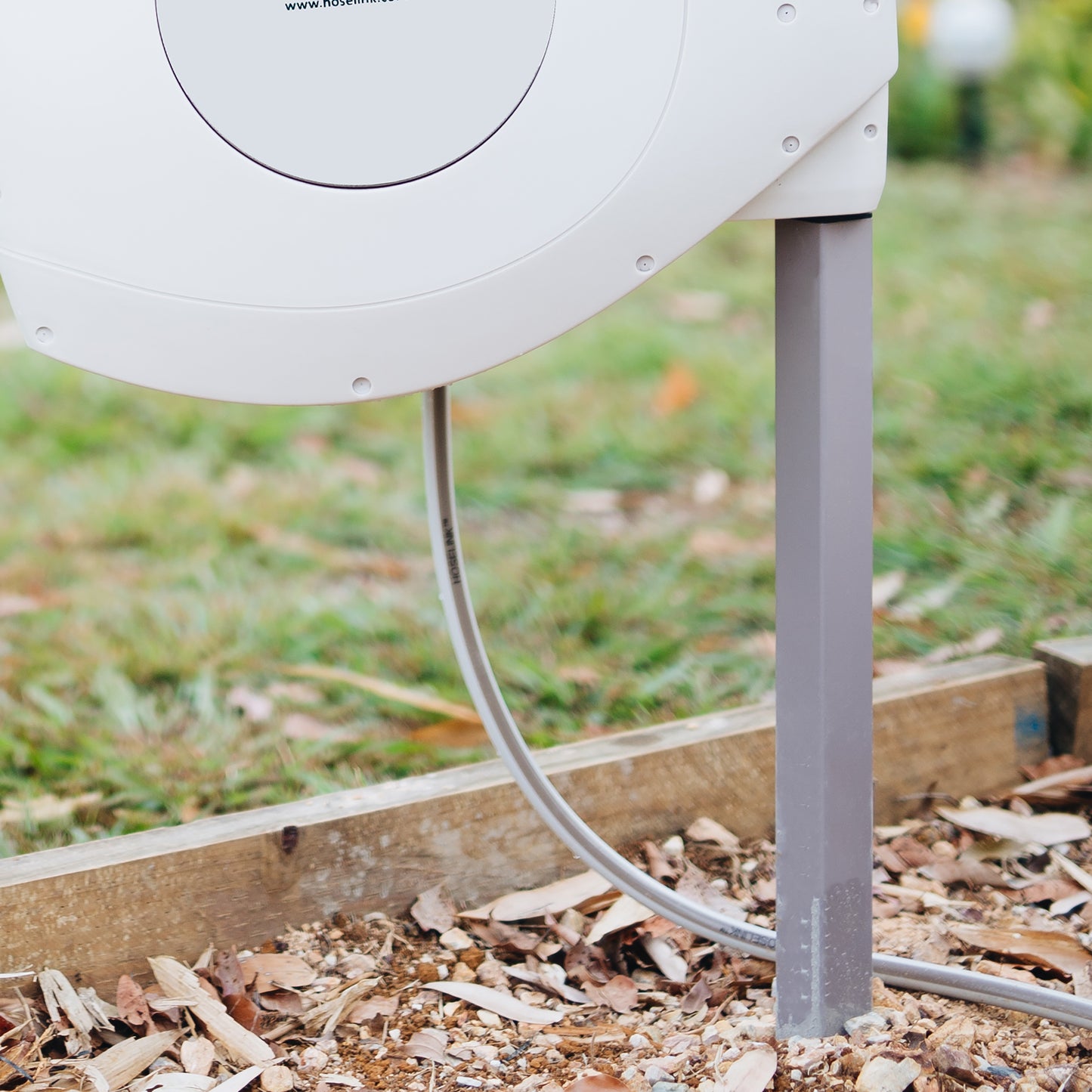 Grey hose reel installed on a grey mounting post in a garden 