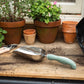 Large Potting Scoop and potted plants with soil on a wooden surface.