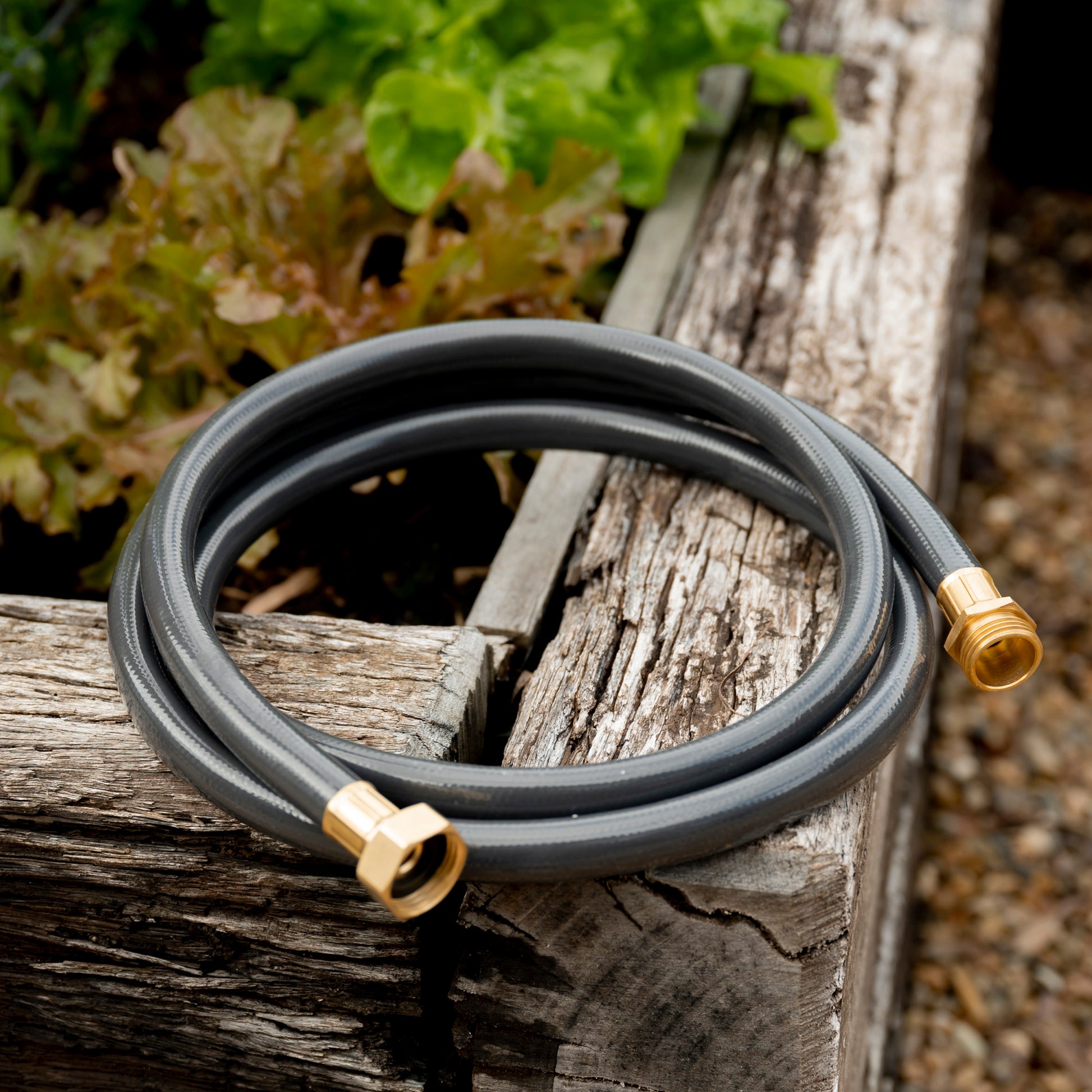 Charcoal Leader Hose for Garden Hose Reels coiled on edge of raised garden bed