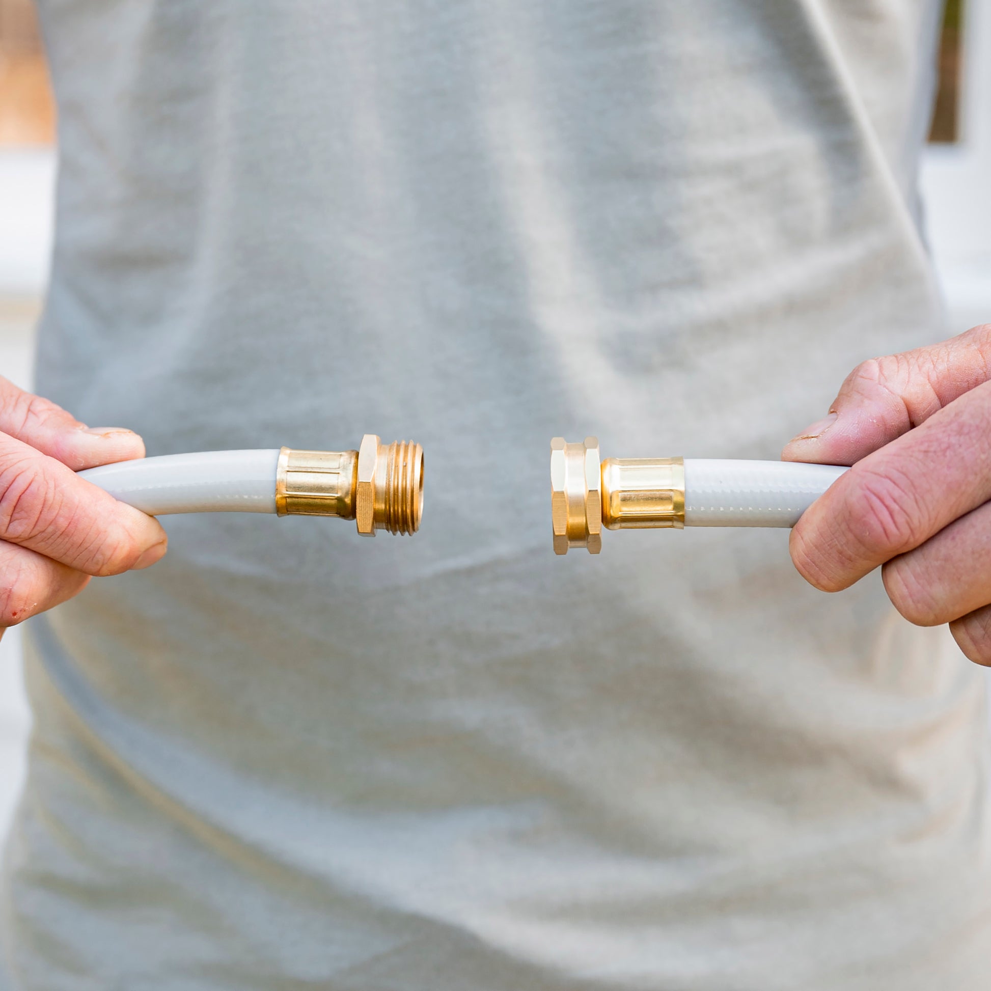 Male holding end of the leader hose and the end of a garden hose close together as if about to connect