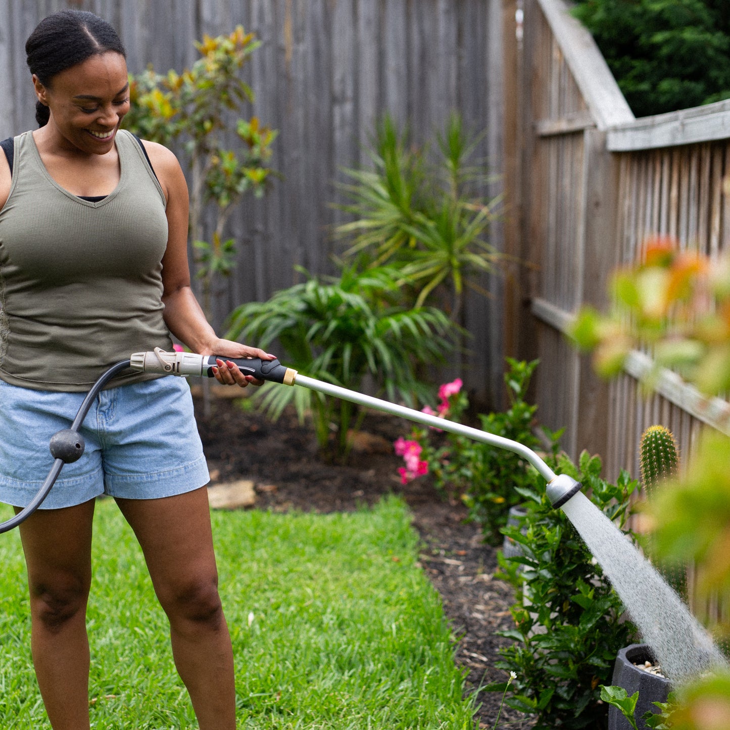 female watering garden plants with the long reach shower wand