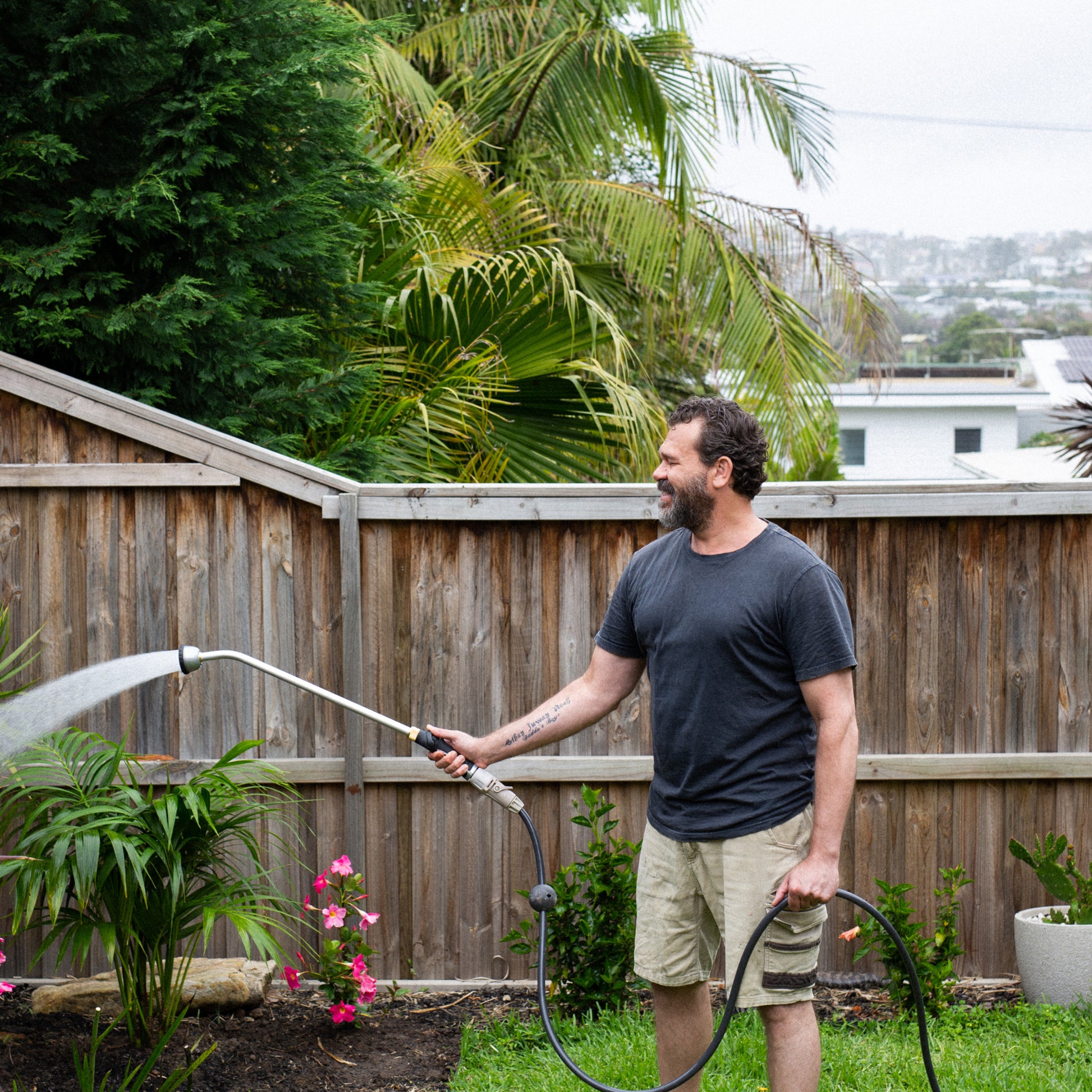 male watering garden plants with the long reach shower wand