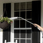 Close up of long reach watering wand watering plants in a hanging basket