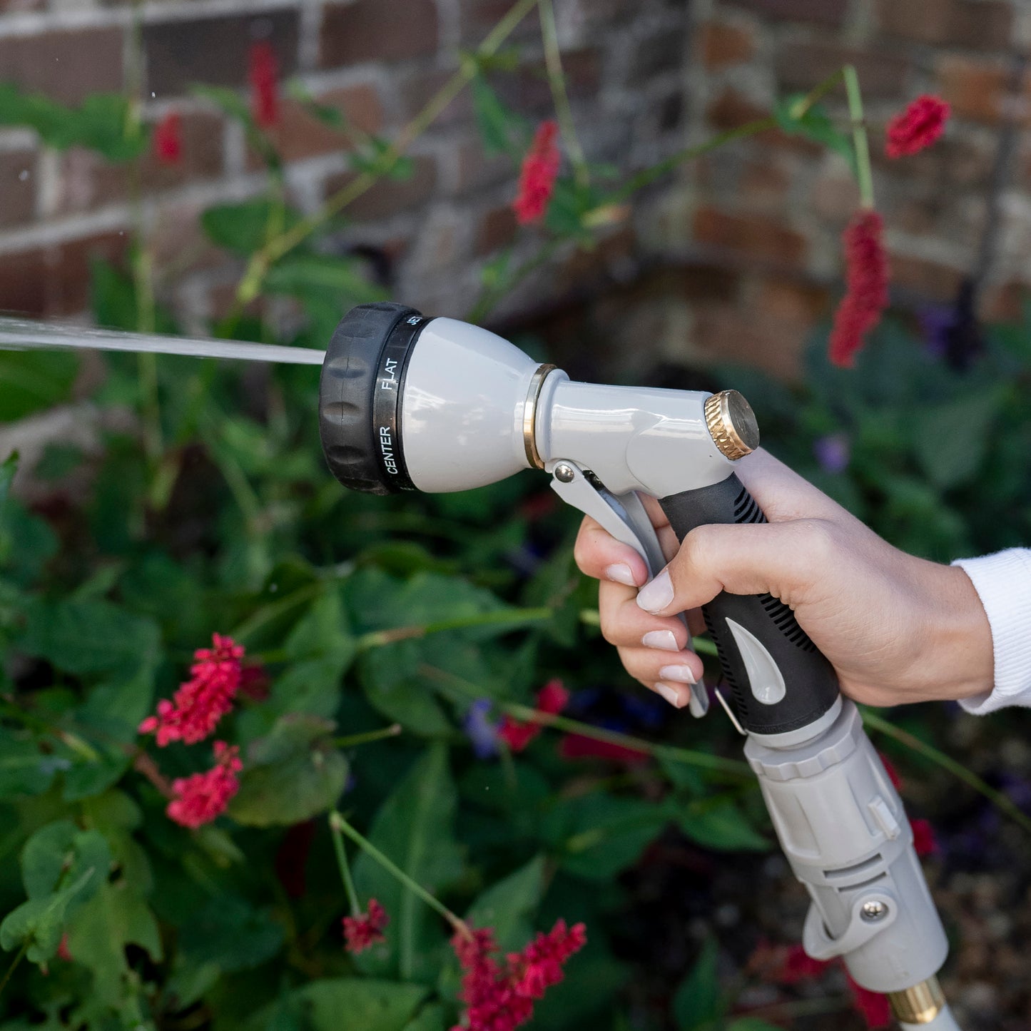 Female holding Metal 7-Function Spray Nozzle using the jet setting in the garden