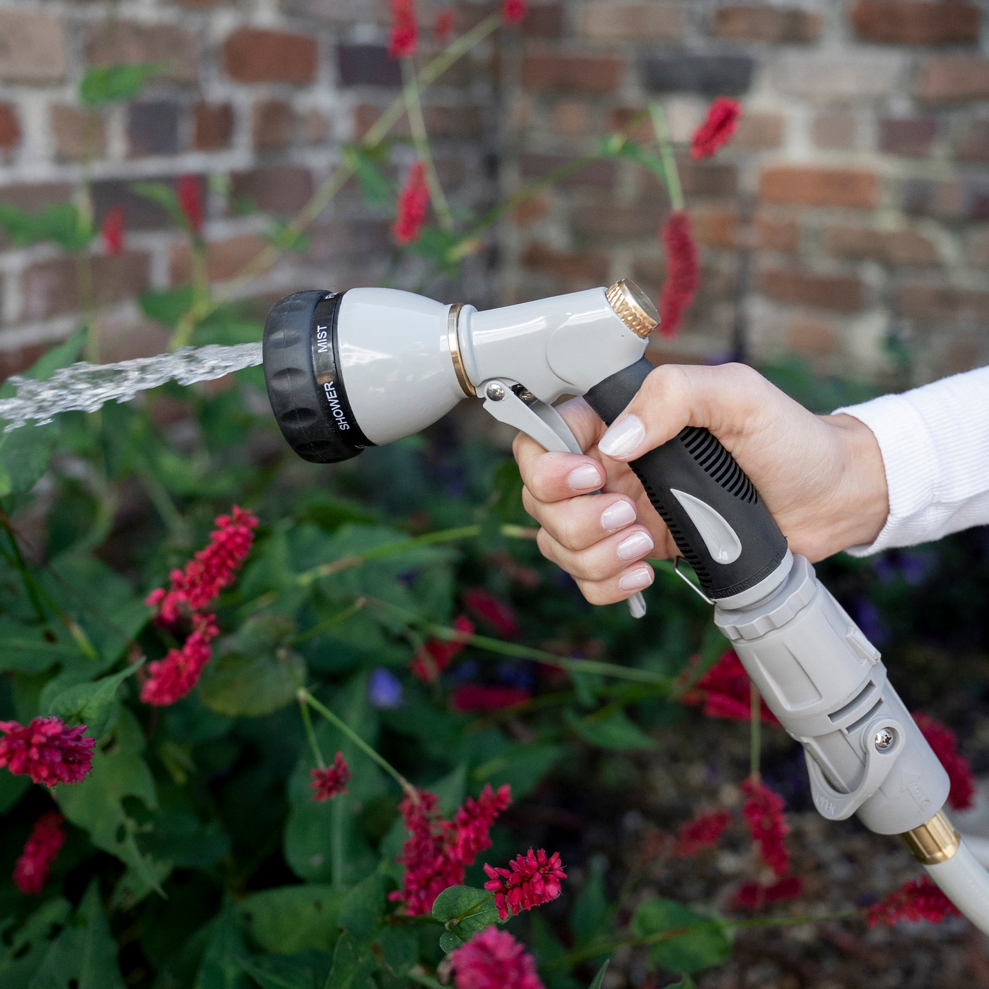 Female holding the 7-Function Spray Nozzle using the full setting to water plants
