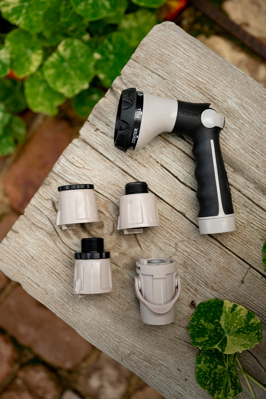 Grey Comfort 8-Pattern Spray Nozzle with four Quick-connect Hose Fittings on garden bench