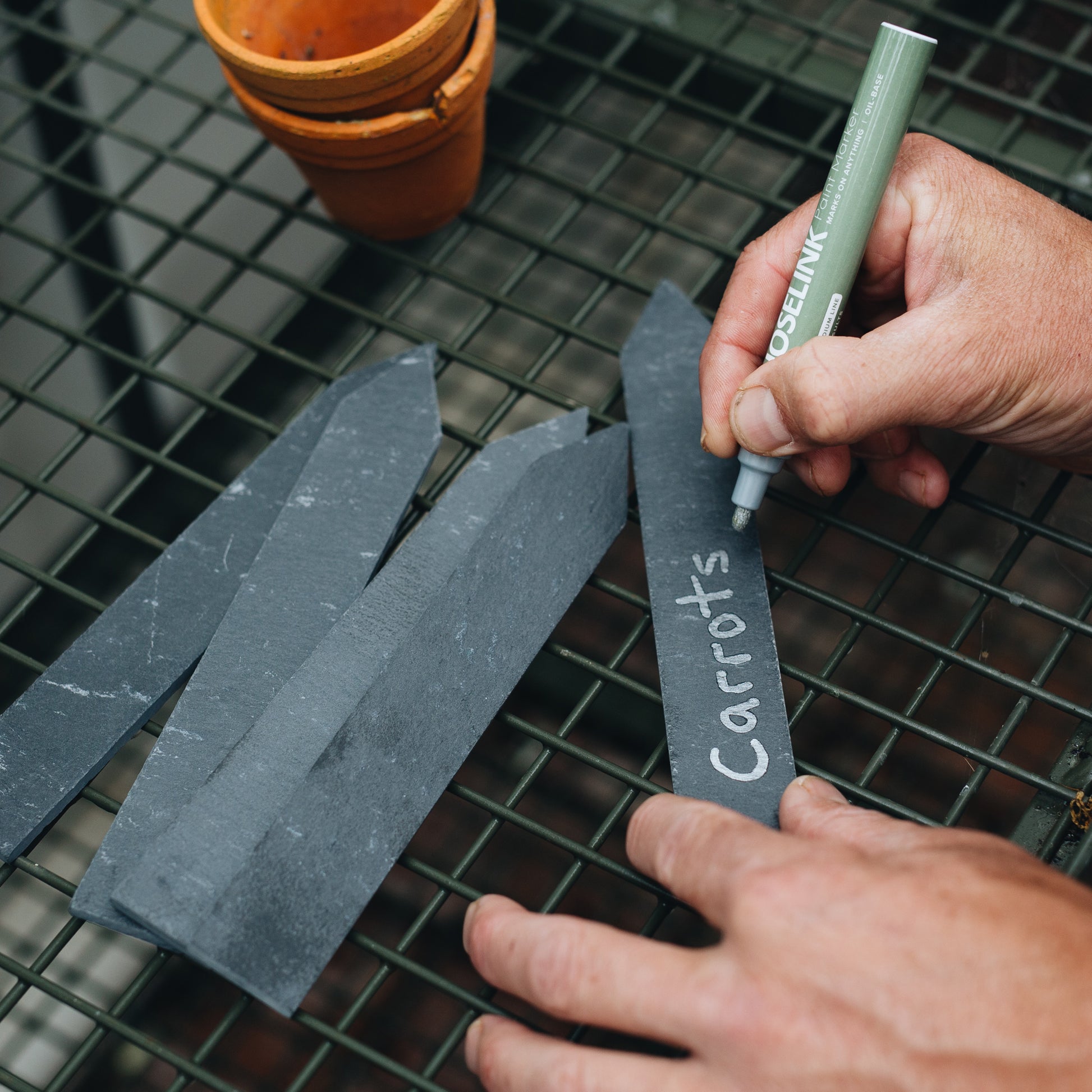 Close up of someone writing with Hoselink's Permanent Marker Pen on a Hoselink Slate Label. 