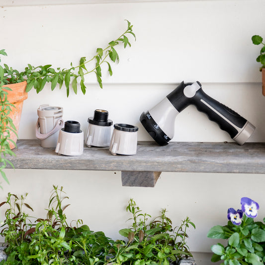 Spray Nozzle and Hose Connectors arranged on a garden shelf next to plants