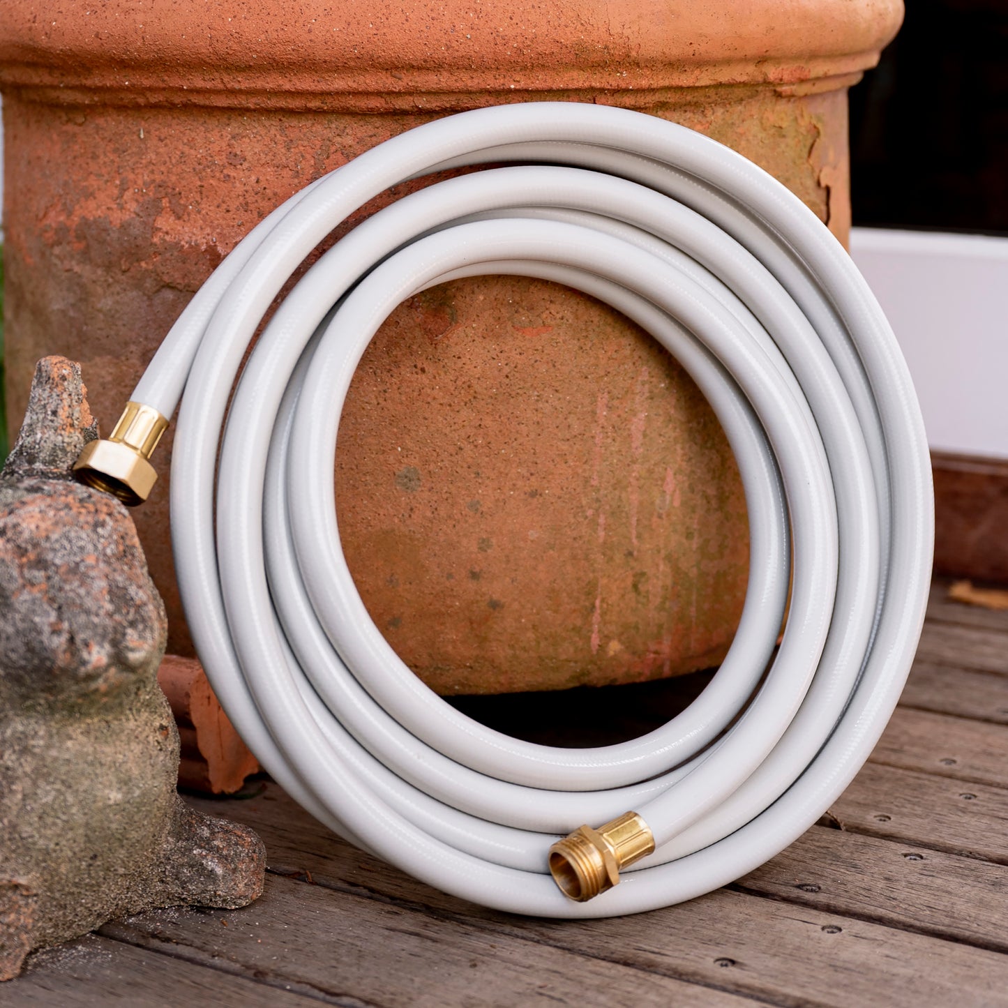 16ft Beige Leader Hose coiled up against terracotta pot