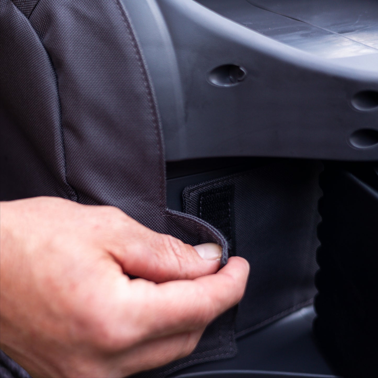 person attaching velcro tab at rear of charcoal evolve hose reel cover