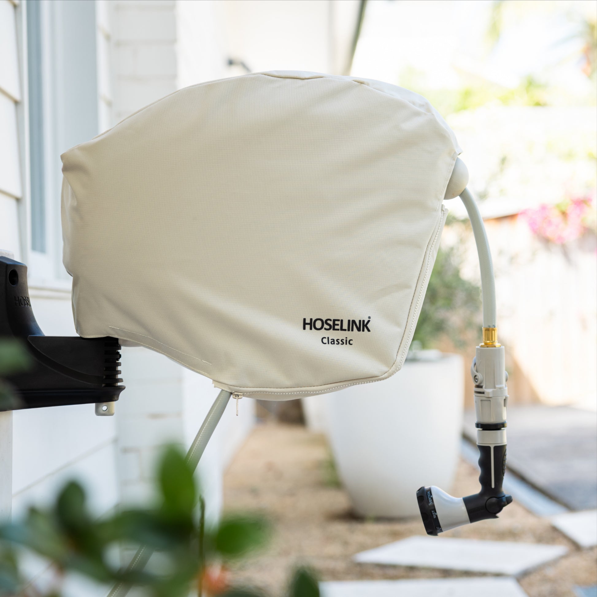 HOSELINK Classic Hose Reel with beige cover installed on a white weatherboard house