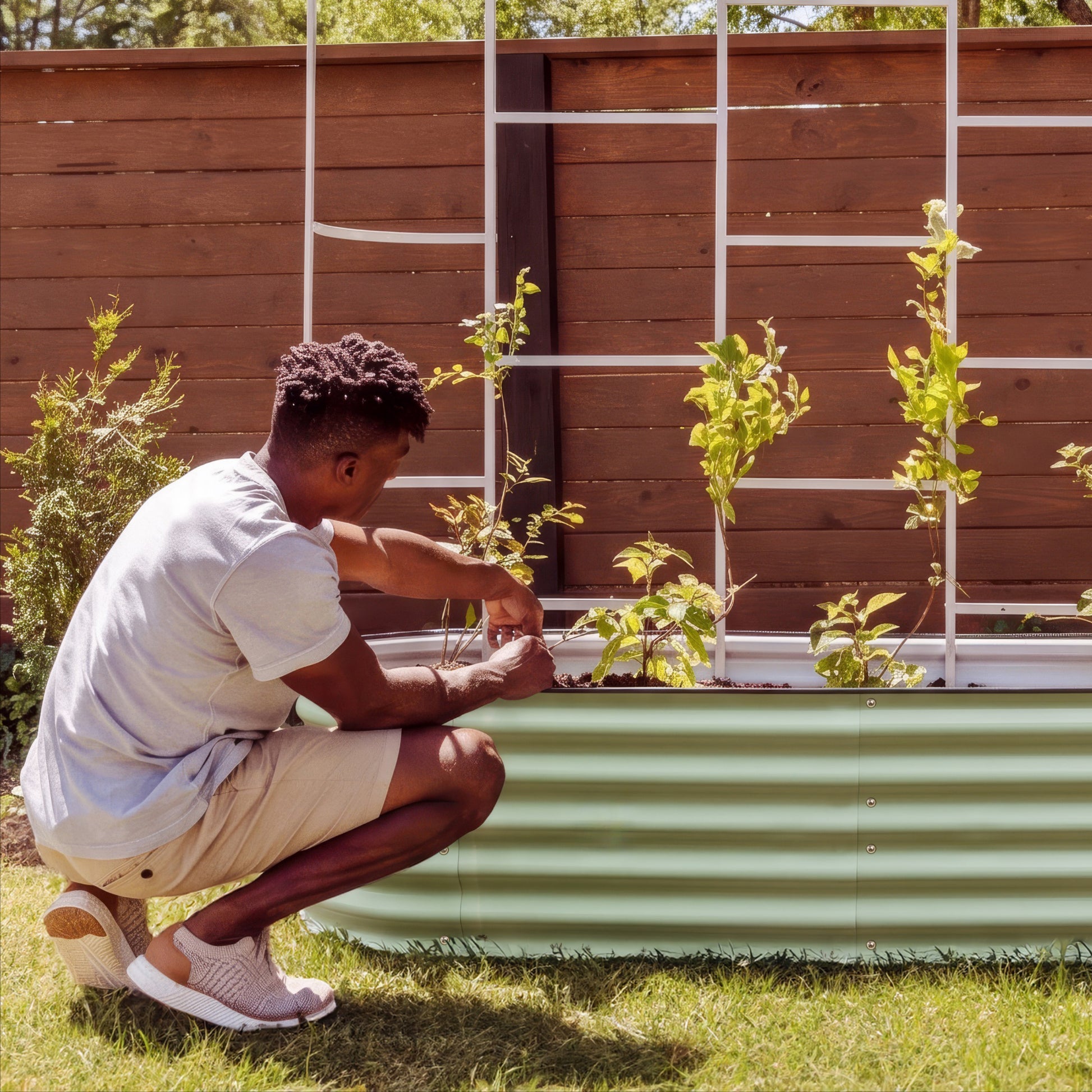 Man attending to his garden bed with plants climbing the trellis in the background