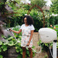 women watering the garden with a beige hose reel