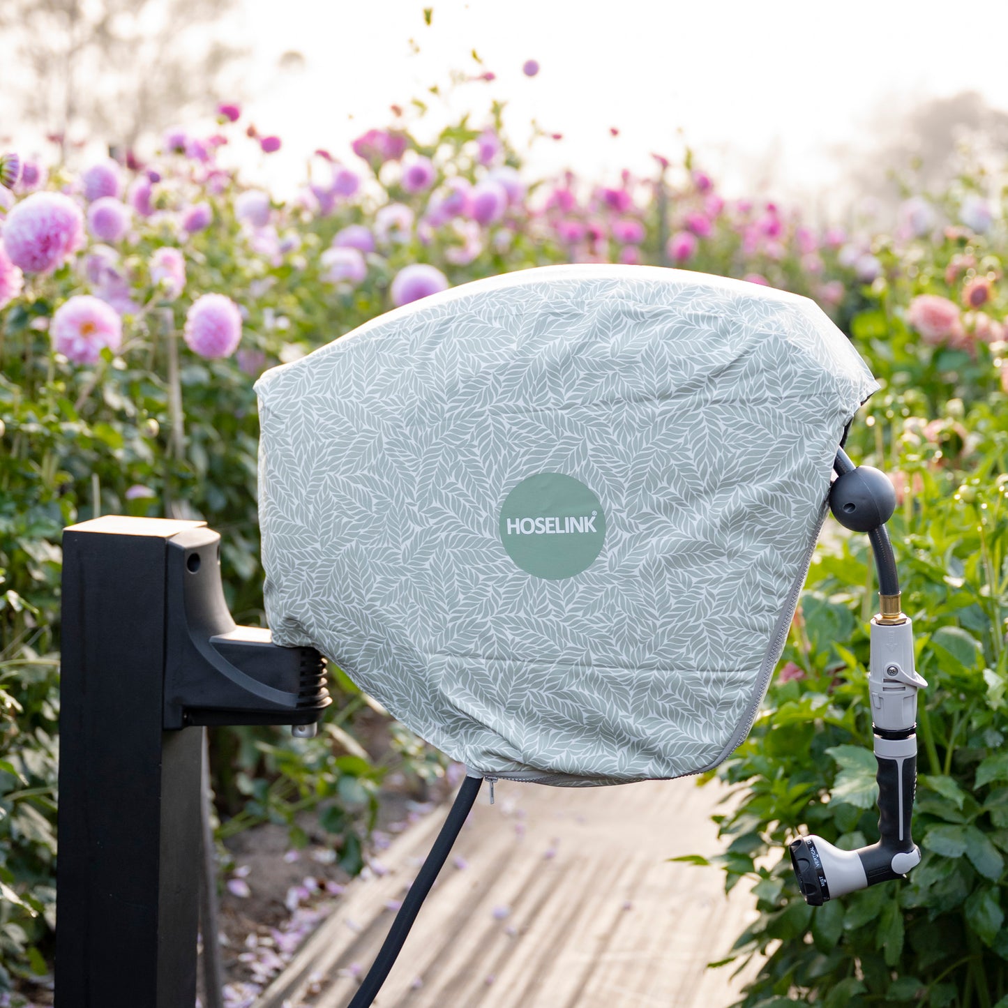 charcoal hose reel mounted amongst flowers with a green fern hose reel cover on it