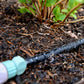 weeper hose and hose connector laying in garden bed with weeper hose on watering the garden