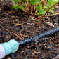 weeper hose and hose connector laying in garden bed with weeper hose on watering the garden