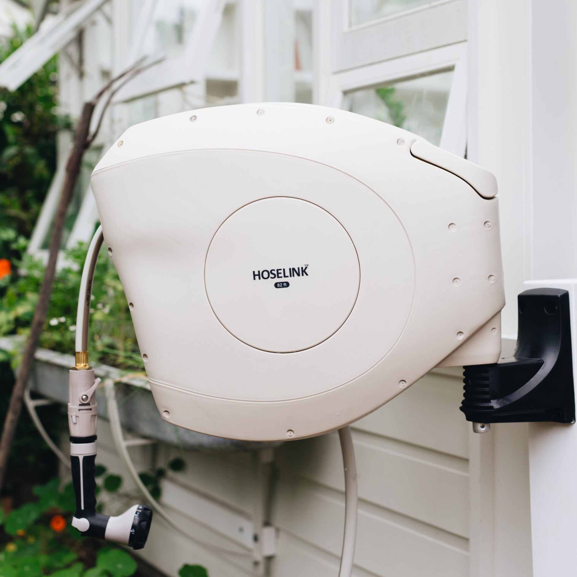 beige hose reel mounted on a post against a beige house